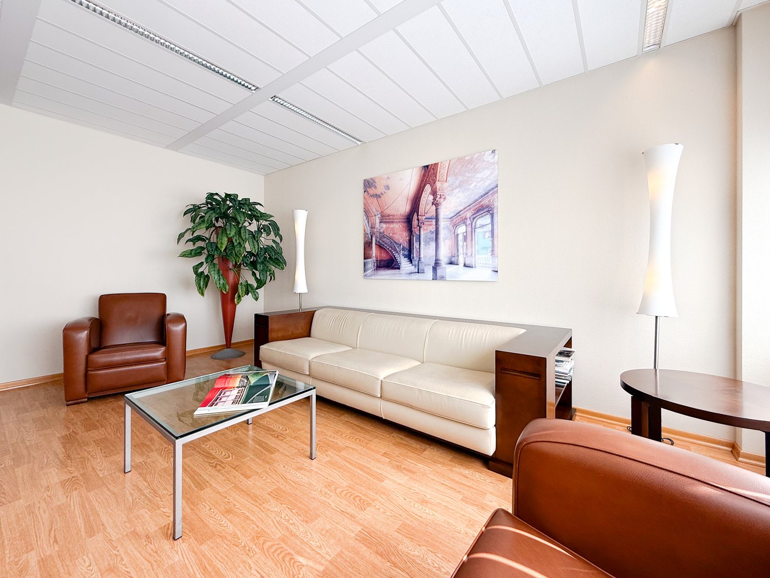Wartezimmer der Praxis mit Ledersofa, Sesseln, Couchtisch und Fensterfront